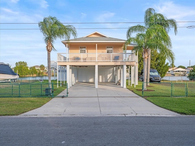 coastal home featuring a balcony, a front yard, and a carport