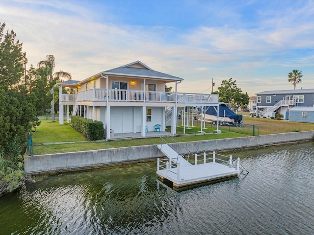 dock area with a lawn, a balcony, and a water view