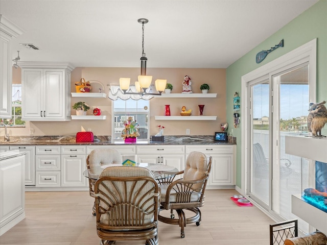 kitchen featuring white cabinetry, hanging light fixtures, light wood-type flooring, and a notable chandelier