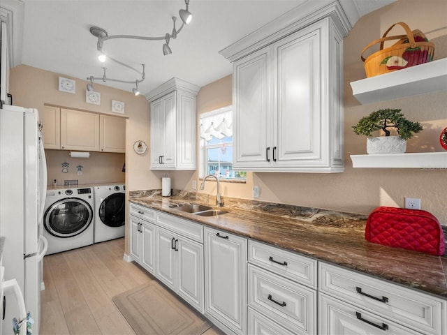 laundry room featuring track lighting, washing machine and dryer, light hardwood / wood-style floors, cabinets, and sink