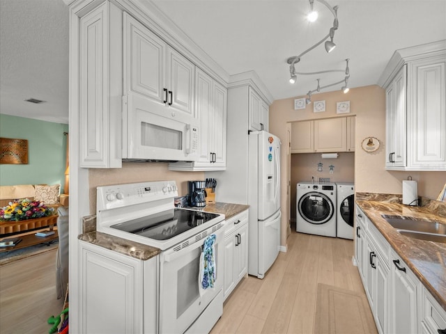 kitchen featuring white appliances, white cabinetry, and independent washer and dryer