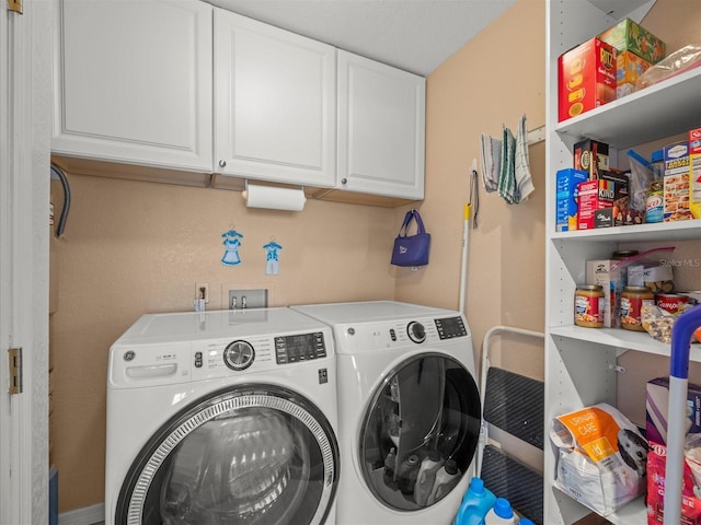 laundry area featuring washing machine and clothes dryer and cabinets