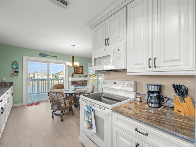 kitchen with white appliances, dark stone counters, pendant lighting, white cabinets, and an inviting chandelier