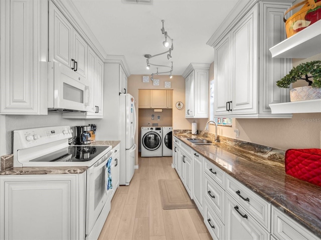 kitchen featuring white appliances, white cabinetry, dark stone counters, sink, and washer and clothes dryer