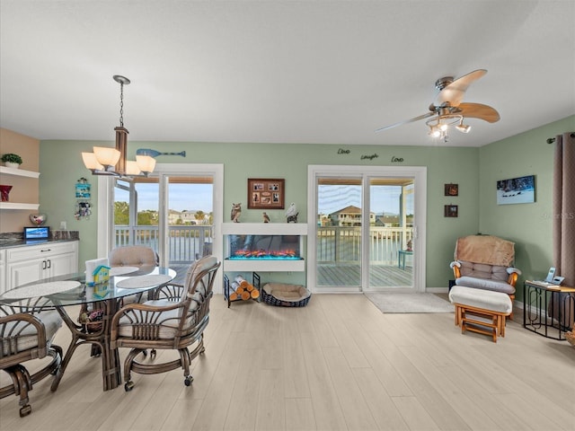 dining space with ceiling fan with notable chandelier, light hardwood / wood-style floors, and a wealth of natural light