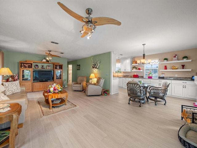 living room featuring lofted ceiling, light wood-type flooring, and ceiling fan with notable chandelier