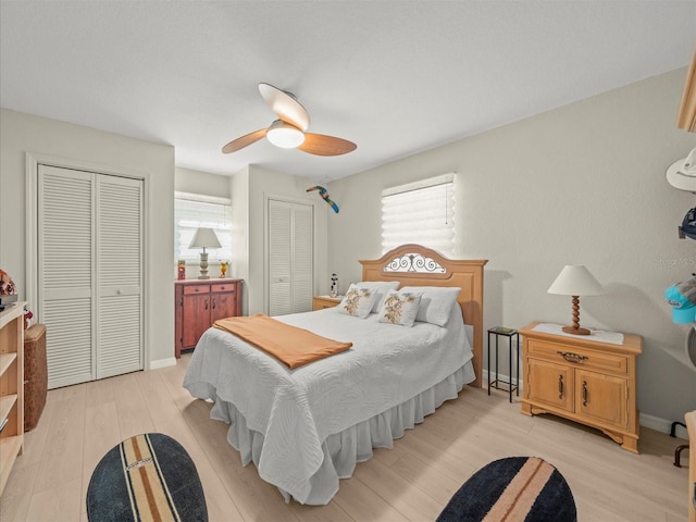 bedroom with ceiling fan, light hardwood / wood-style floors, multiple closets, and multiple windows