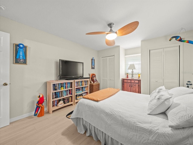 bedroom with light wood-type flooring, two closets, and ceiling fan