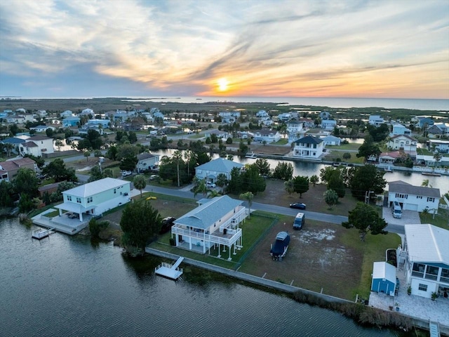 aerial view at dusk featuring a water view