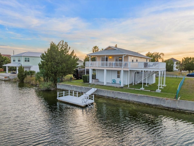 view of dock with a yard and a water view