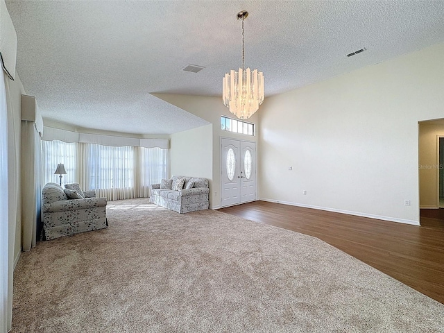 carpeted foyer entrance with a textured ceiling and a notable chandelier