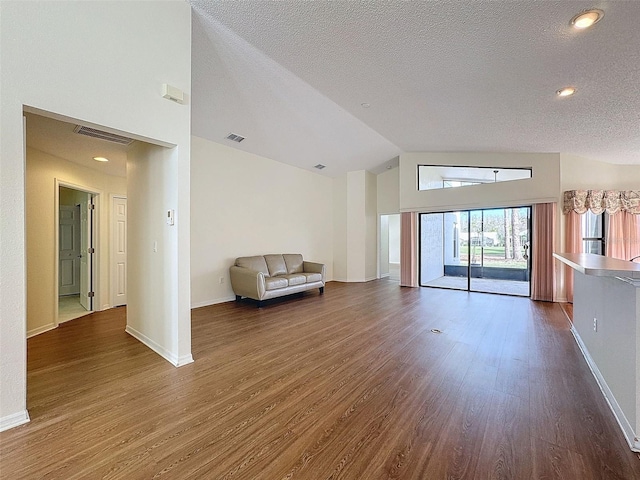 unfurnished room featuring a textured ceiling, vaulted ceiling, and dark wood-type flooring