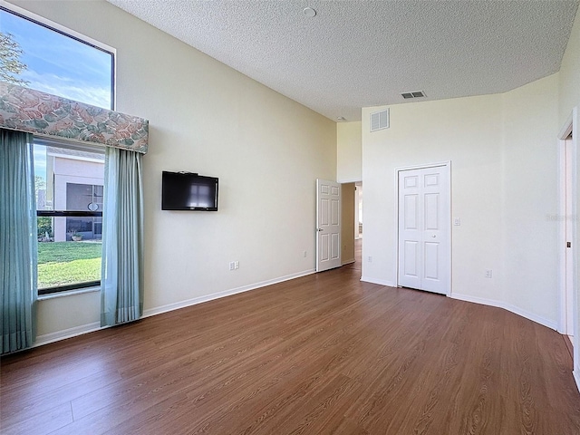 empty room featuring lofted ceiling, dark wood-type flooring, and a textured ceiling