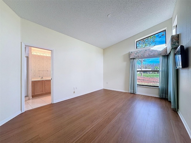 spare room featuring light wood-type flooring and a textured ceiling