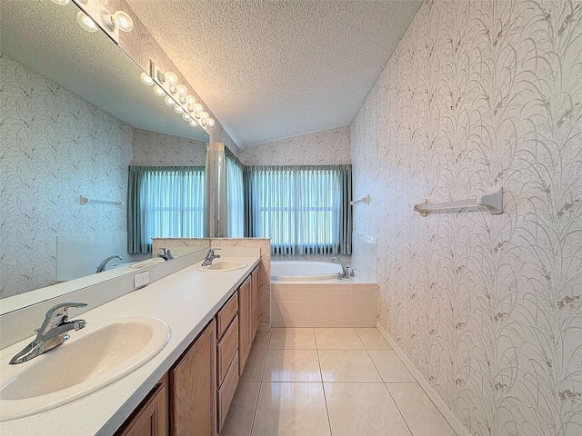 bathroom featuring tile patterned flooring, a relaxing tiled tub, vaulted ceiling, a textured ceiling, and vanity