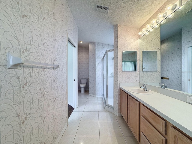 bathroom featuring tile patterned flooring, an enclosed shower, a textured ceiling, toilet, and vanity