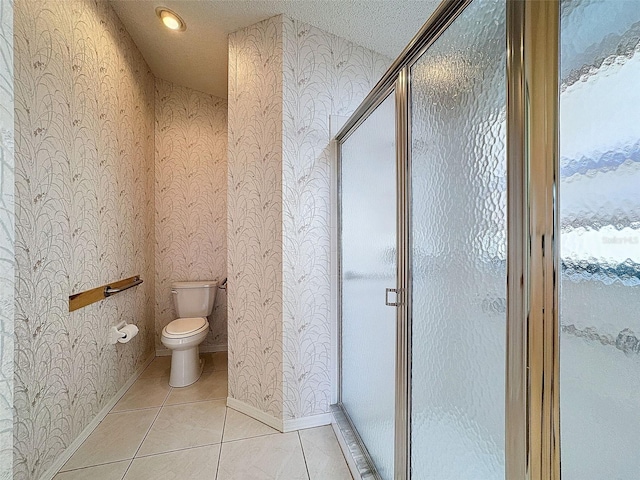 bathroom with tile patterned flooring, a textured ceiling, toilet, and walk in shower