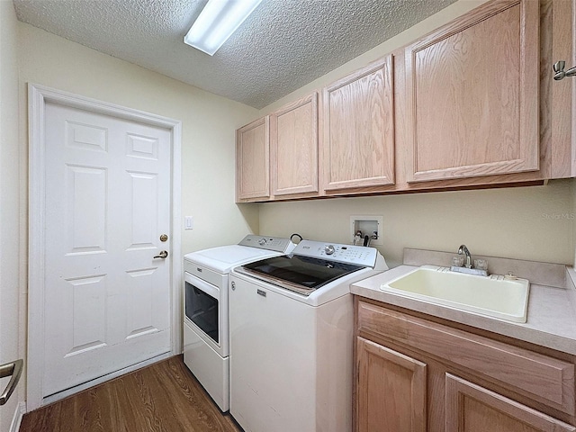 washroom with washing machine and clothes dryer, sink, cabinets, dark hardwood / wood-style floors, and a textured ceiling