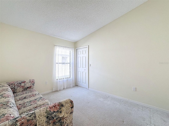 sitting room with vaulted ceiling, light colored carpet, and a textured ceiling