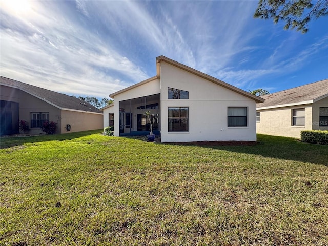 rear view of house featuring a sunroom and a yard