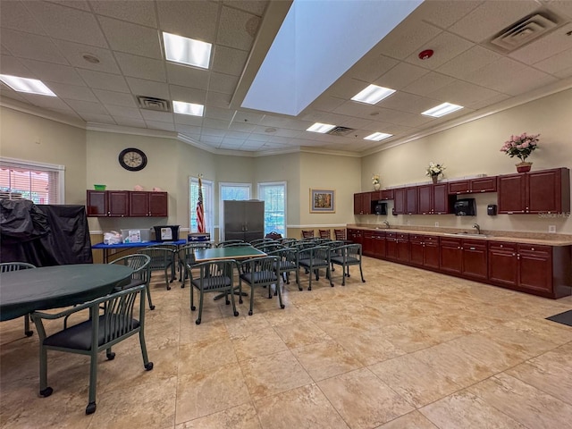 dining space with a drop ceiling, crown molding, and sink