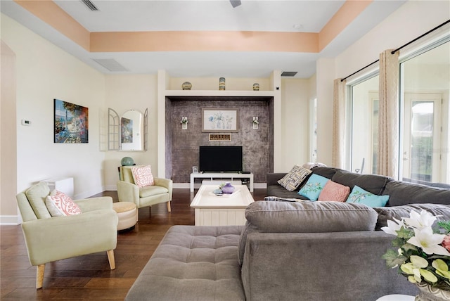 living room featuring dark wood-type flooring and a tray ceiling