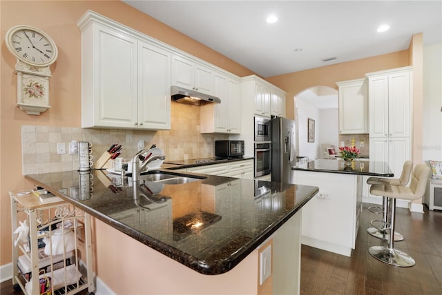 kitchen featuring dark wood-type flooring, kitchen peninsula, a kitchen bar, white cabinets, and black appliances