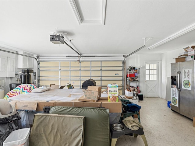 garage featuring a garage door opener and stainless steel refrigerator with ice dispenser