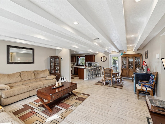 living room featuring beamed ceiling and a textured ceiling