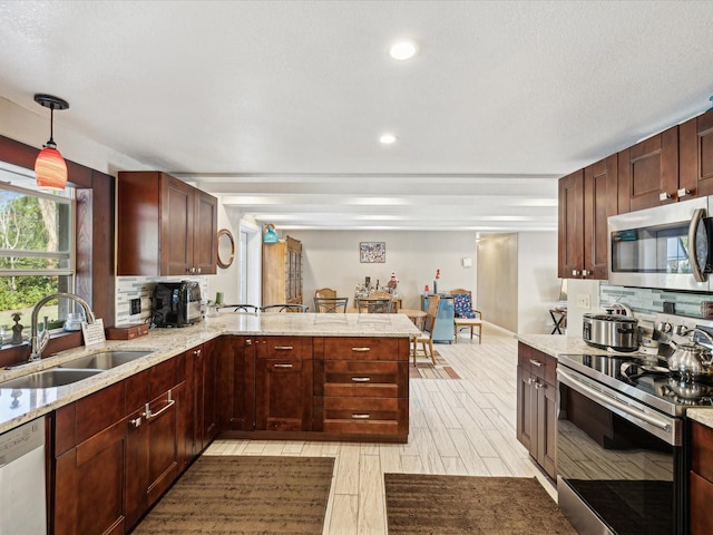 kitchen featuring kitchen peninsula, appliances with stainless steel finishes, decorative backsplash, and sink