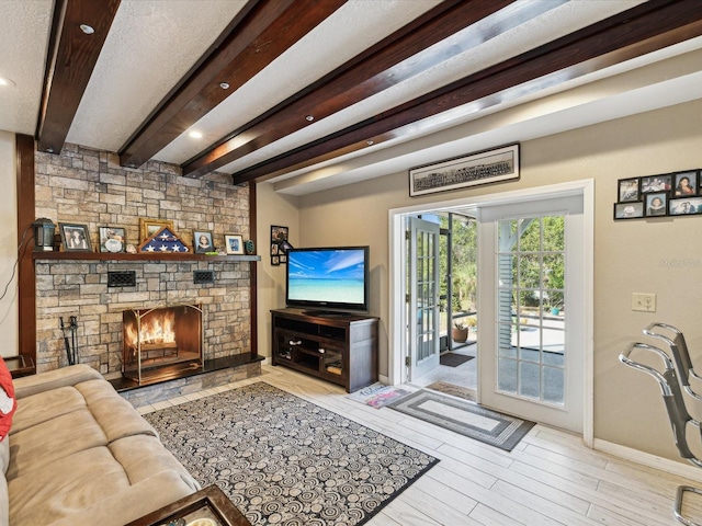 living room featuring beam ceiling and a stone fireplace