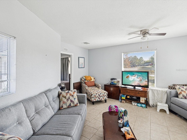 living room with ceiling fan, light tile patterned flooring, and a textured ceiling