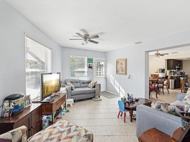 tiled living room with a textured ceiling and ceiling fan