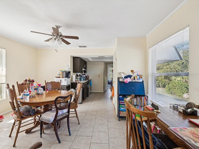 tiled dining space featuring a textured ceiling, ceiling fan, and crown molding