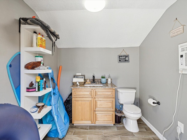 bathroom with vanity, toilet, and vaulted ceiling