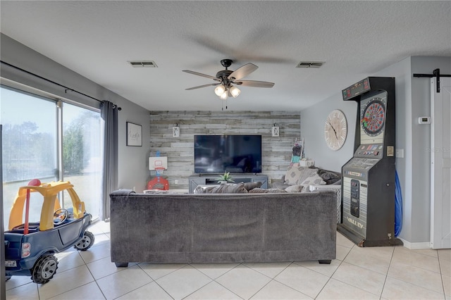 tiled living room featuring a textured ceiling, ceiling fan, and wood walls