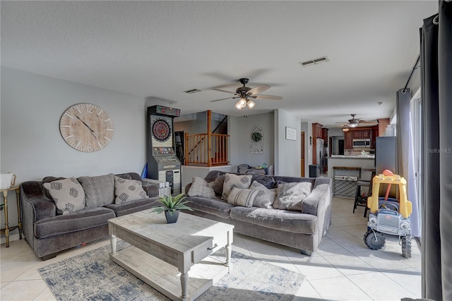 living room with ceiling fan, light tile patterned flooring, and a textured ceiling