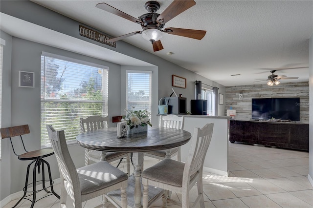 dining space with ceiling fan, light tile patterned floors, and a textured ceiling