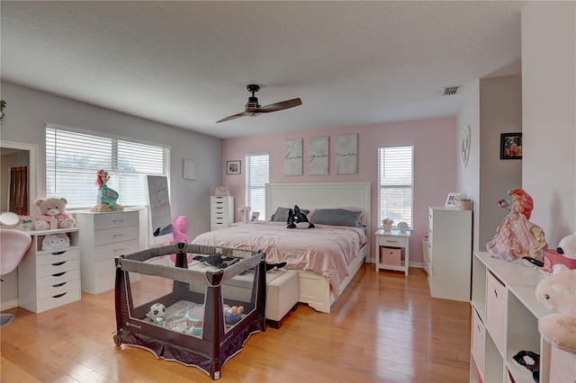 bedroom featuring ceiling fan, a textured ceiling, and light wood-type flooring