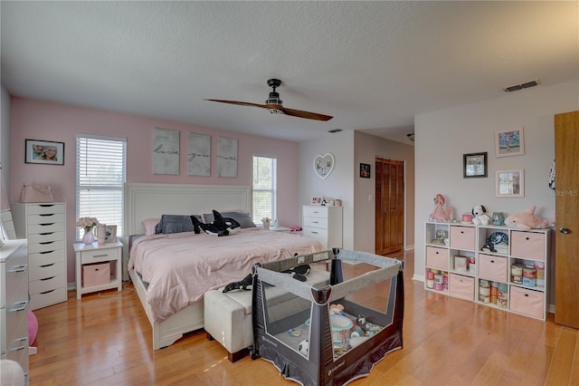 bedroom featuring a textured ceiling, light hardwood / wood-style flooring, and ceiling fan