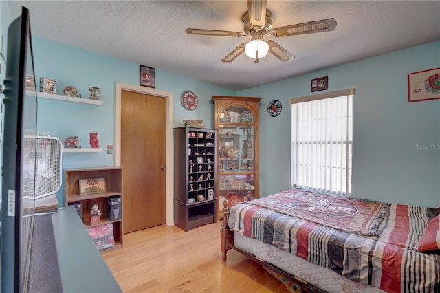 bedroom with ceiling fan, a textured ceiling, and light hardwood / wood-style flooring