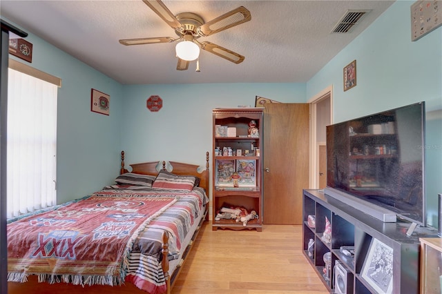 bedroom with a textured ceiling, light wood-type flooring, and ceiling fan