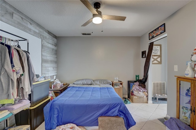 tiled bedroom with ceiling fan, a textured ceiling, and wooden walls