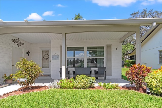 entrance to property with a lawn and covered porch