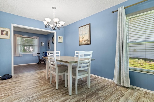 dining space featuring hardwood / wood-style floors, a textured ceiling, a notable chandelier, and a healthy amount of sunlight