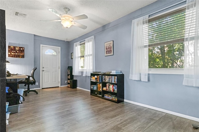 office featuring hardwood / wood-style flooring, ceiling fan, a textured ceiling, and a wealth of natural light