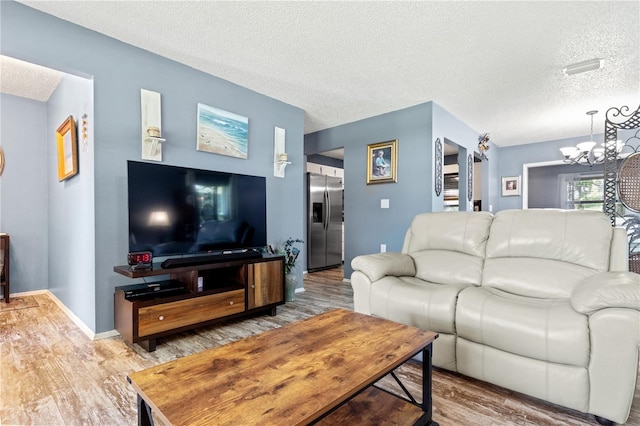 living room featuring a notable chandelier, wood-type flooring, and a textured ceiling