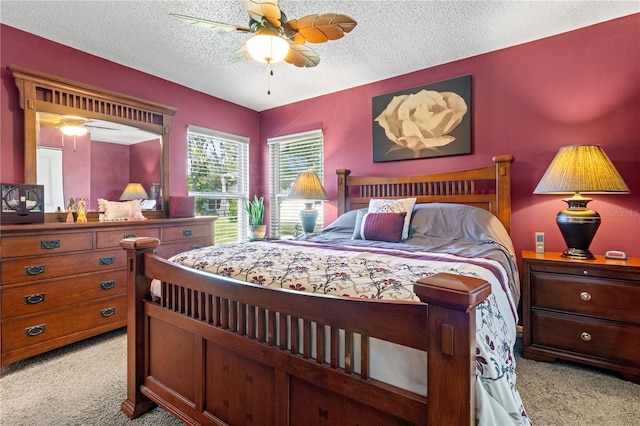 bedroom with ceiling fan, light colored carpet, and a textured ceiling