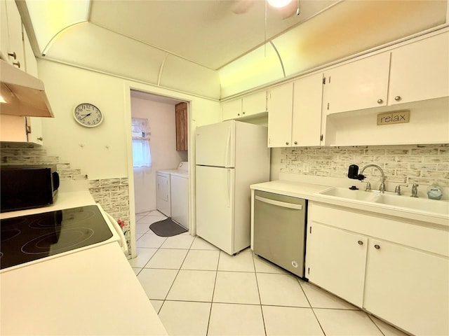 kitchen with washing machine and clothes dryer, sink, light tile patterned flooring, white appliances, and white cabinets