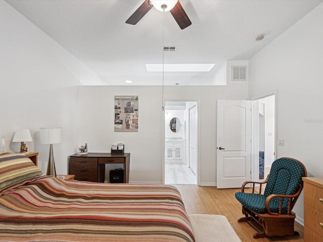 bedroom featuring a skylight, visible vents, connected bathroom, and light wood finished floors